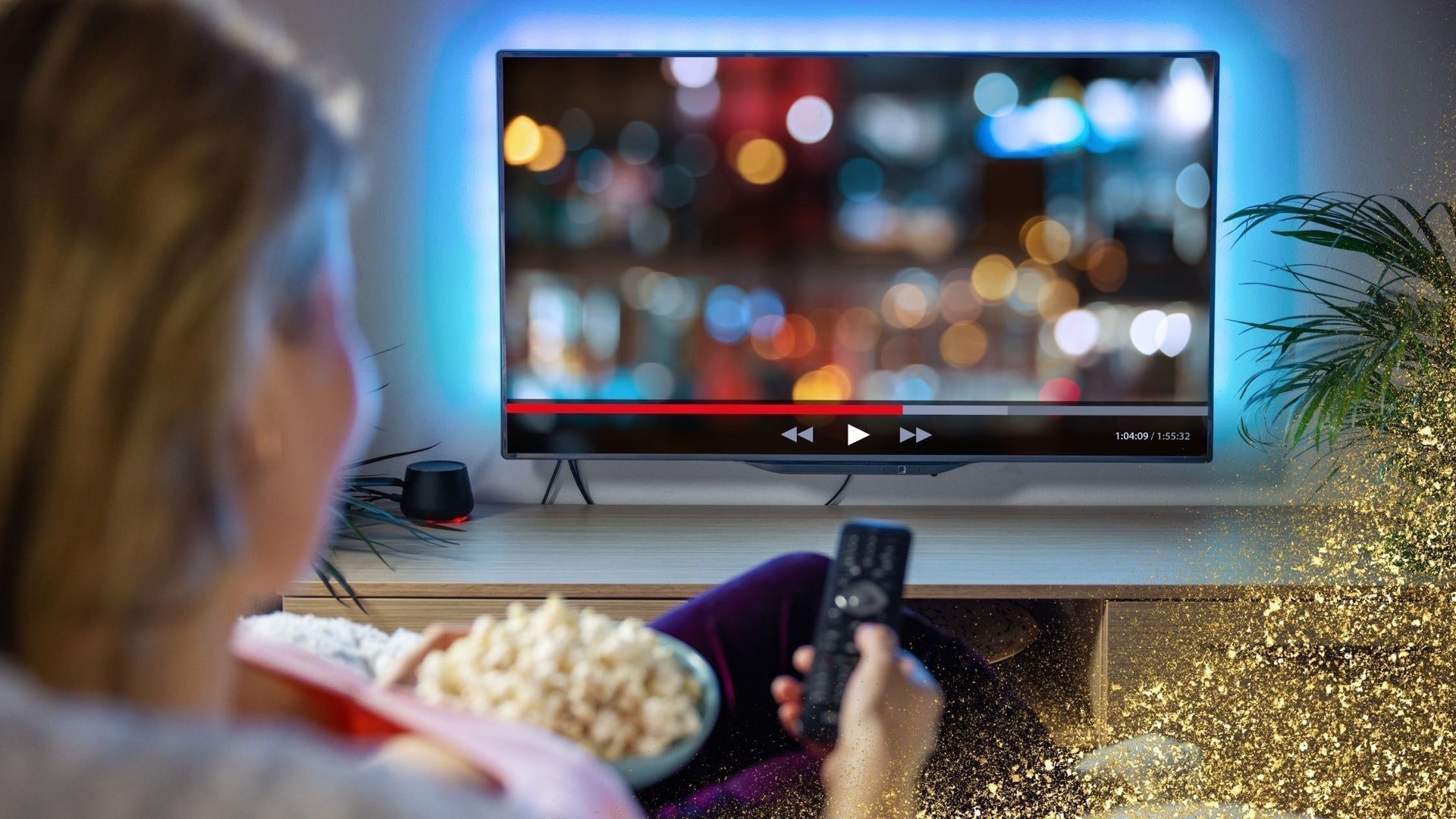 Person sitting on a couch watching a movie on a flat-screen TV, holding a remote and a bowl of popcorn, with blurred city lights on the screen and golden sparkles in the foreground.